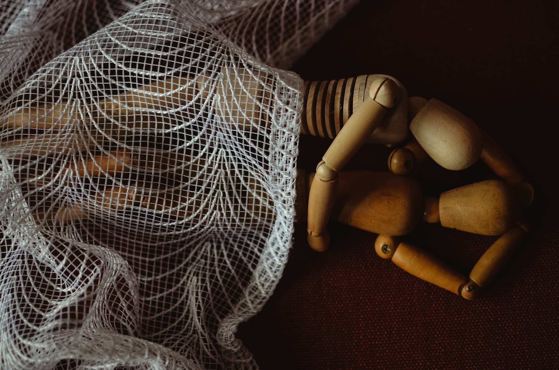 Two wooden dolls in bed together cuddling